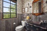 This charming bathroom features rustic wood paneling and a unique copper sink, creating a warm and inviting atmosphere.