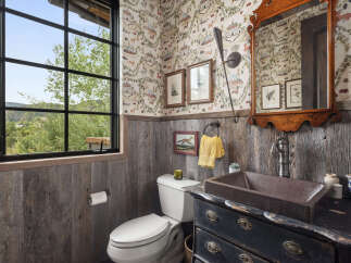 This charming bathroom features rustic wood paneling and a unique copper sink, creating a warm and inviting atmosphere.