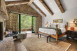 Experience luxury in this stunning bedroom featuring exposed wooden beams and a stone accent wall.