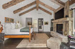 This stunning bedroom boasts a rustic charm with exposed wooden beams and a stone fireplace, creating a warm and inviting atmosphere.