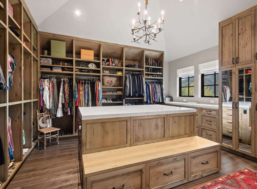 Step into luxury with this stunning walk-in closet, featuring custom wooden cabinetry and ample storage space.