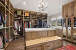 Step into luxury with this stunning walk-in closet, featuring custom wooden cabinetry and ample storage space.