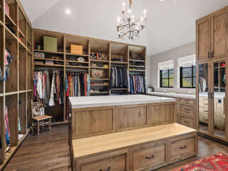 Step into luxury with this stunning walk-in closet, featuring custom wooden cabinetry and ample storage space.