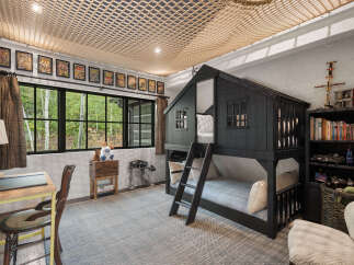 This charming bedroom features a unique bunk bed designed to resemble a house, perfect for a child's imaginative play.
