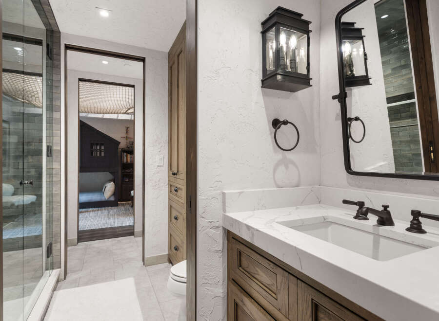 This luxurious bathroom features a modern design with a marble countertop and dark fixtures.