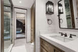 This luxurious bathroom features a modern design with a marble countertop and dark fixtures.
