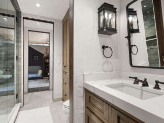 This luxurious bathroom features a modern design with a marble countertop and dark fixtures.