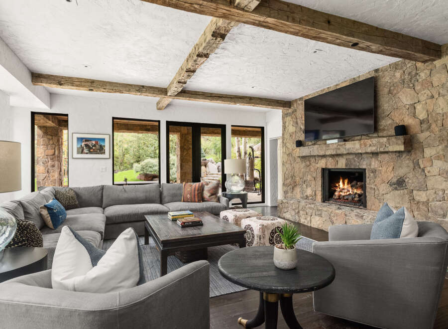 Experience luxury living in this stunning property featuring a cozy living room with a stone fireplace and a large flat-screen TV.