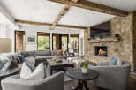 Experience luxury living in this stunning property featuring a cozy living room with a stone fireplace and a large flat-screen TV.