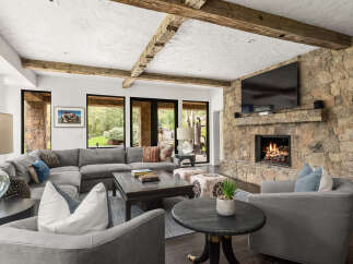 Experience luxury living in this stunning property featuring a cozy living room with a stone fireplace and a large flat-screen TV.