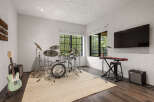 This music room is a dream come true for any musician, featuring a full drum set, keyboard, and guitar.