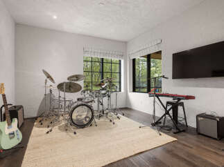 This music room is a dream come true for any musician, featuring a full drum set, keyboard, and guitar.