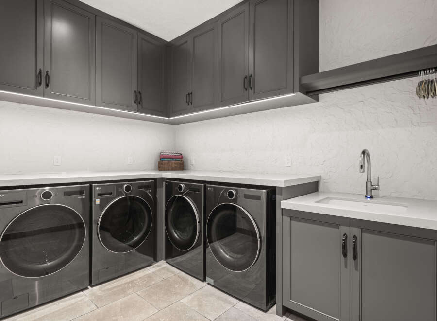 This modern laundry room features sleek gray cabinetry and countertops, creating a stylish and functional space.