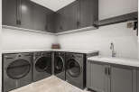 This modern laundry room features sleek gray cabinetry and countertops, creating a stylish and functional space.