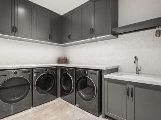 This modern laundry room features sleek gray cabinetry and countertops, creating a stylish and functional space.