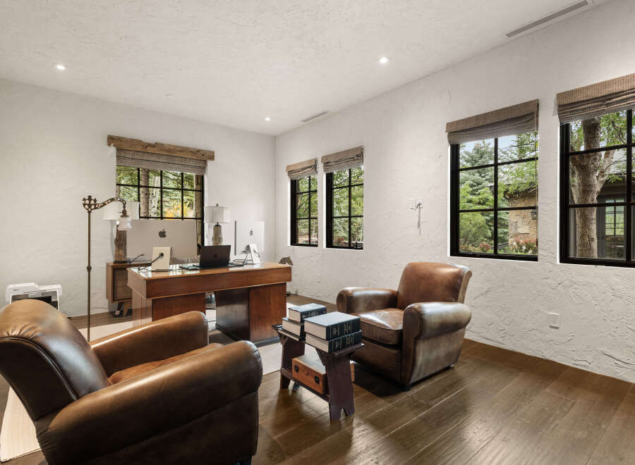 This luxurious home office boasts a sophisticated design with rich wooden accents and comfortable leather seating.