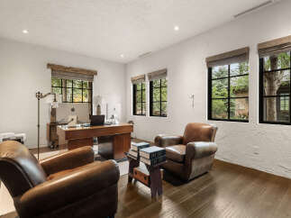 This luxurious home office boasts a sophisticated design with rich wooden accents and comfortable leather seating.