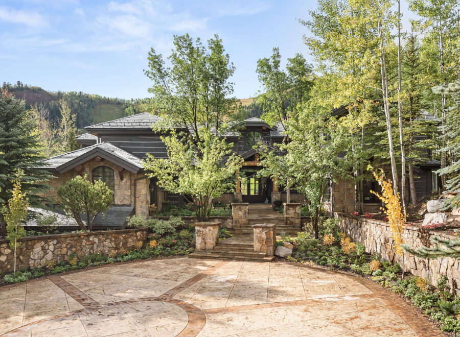 This stunning property showcases a luxurious stone facade and a beautifully landscaped entrance, creating an inviting first impression.