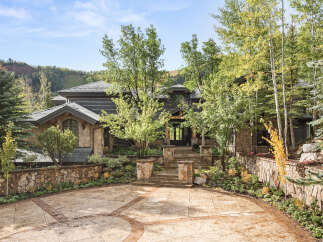 This stunning property showcases a luxurious stone facade and a beautifully landscaped entrance, creating an inviting first impression.