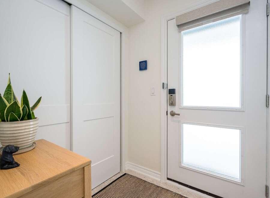 Step into this inviting entryway, showcasing a modern design with sleek white doors and a stylish wooden console.