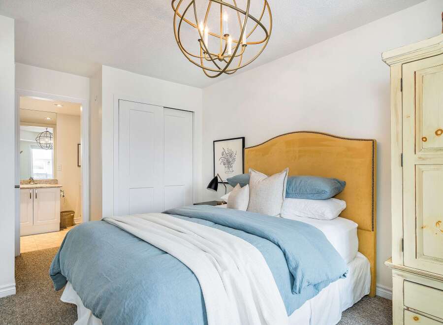 This inviting bedroom features a stylish bed with a tufted headboard and soft bedding, creating a cozy and relaxing atmosphere.