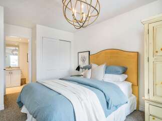 This inviting bedroom features a stylish bed with a tufted headboard and soft bedding, creating a cozy and relaxing atmosphere.