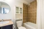 This bathroom features a clean and modern design with a round mirror, a white cabinet, and a toilet.