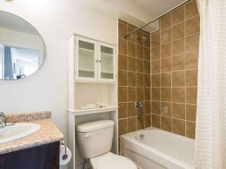 This bathroom features a clean and modern design with a round mirror, a white cabinet, and a toilet.