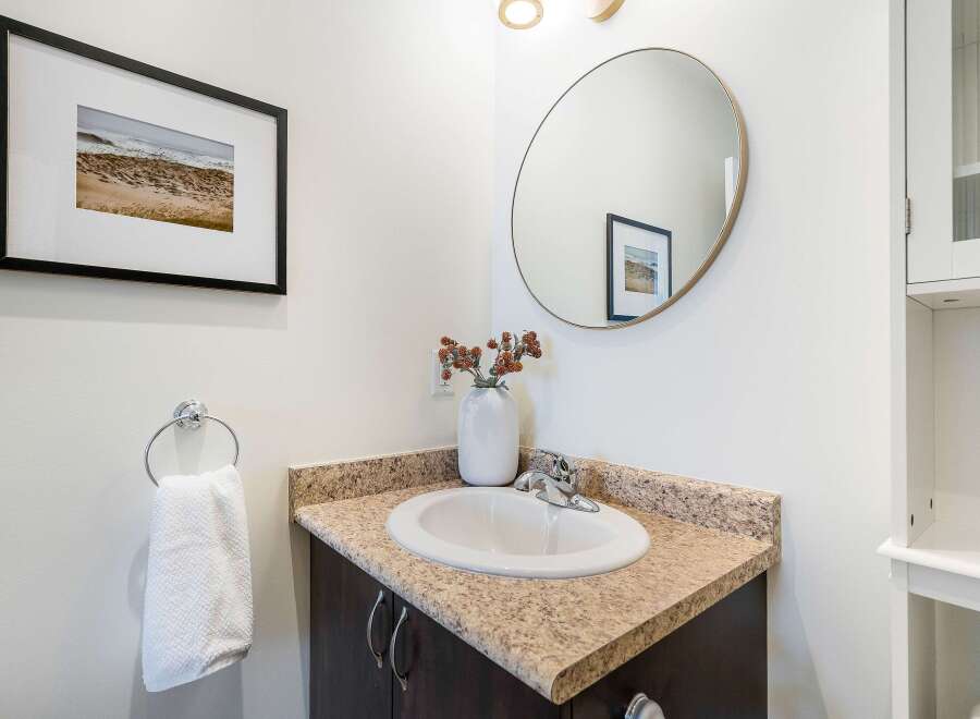 This stunning bathroom features a modern design with a sleek vanity and a stylish round mirror.