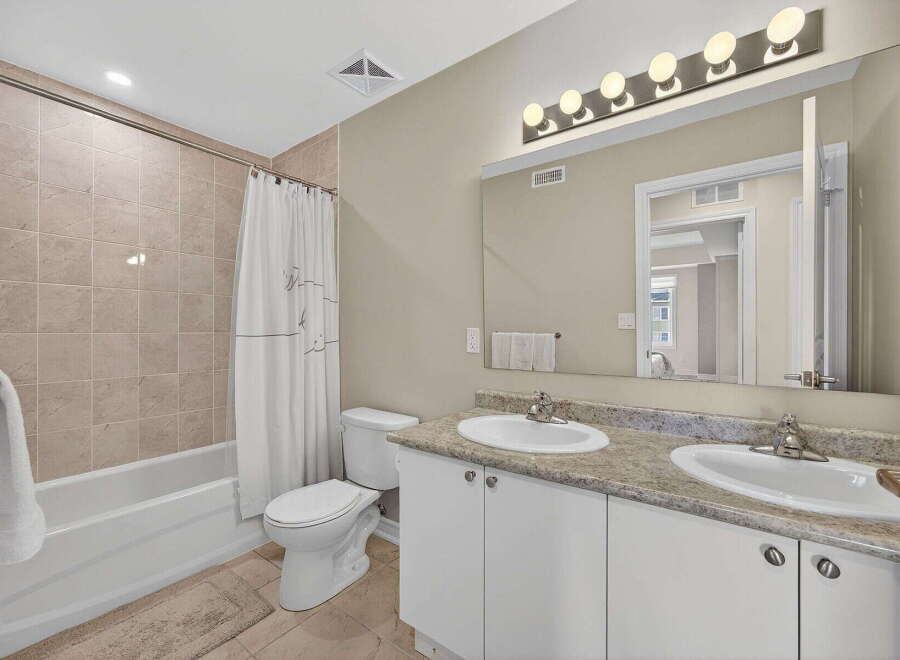 Step into this beautifully designed bathroom, featuring a modern vanity with dual sinks and ample storage.