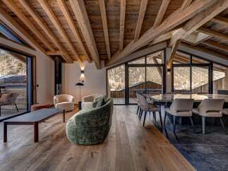 Experience luxury living in this stunning chalet, featuring a spacious open-plan design with exposed wooden beams and large windows that offer breathtaking mountain views.