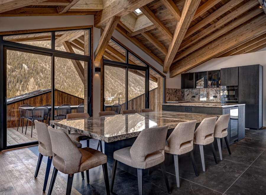 Experience luxury living in this stunning property featuring a spacious dining area with a large marble table and comfortable seating.