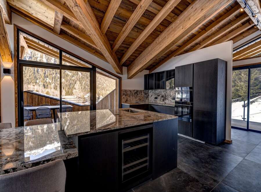 Experience luxury living in this stunning property, featuring a modern kitchen with sleek black cabinetry and a granite countertop island.