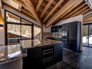 Experience luxury living in this stunning property, featuring a modern kitchen with sleek black cabinetry and a granite countertop island.