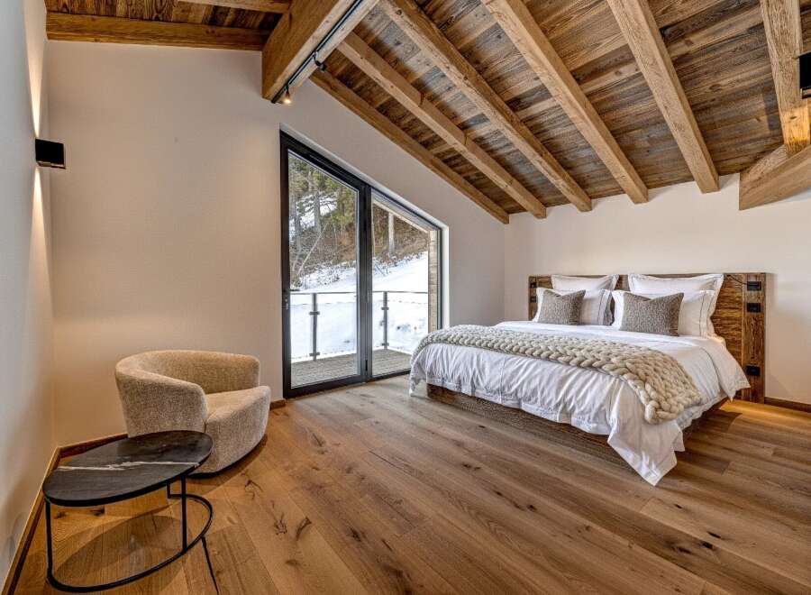 Experience luxury living in this stunning bedroom with a rustic wooden ceiling and hardwood floors.