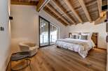 Experience luxury living in this stunning bedroom with a rustic wooden ceiling and hardwood floors.