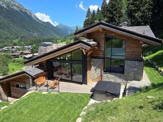 Experience luxury mountain living in this stunning chalet, featuring expansive glass windows that frame breathtaking alpine views.