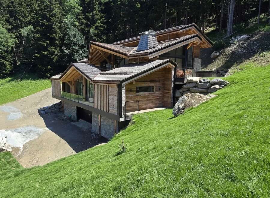 Nestled on a lush green hillside, this modern chalet boasts a striking architectural design with extensive use of natural wood and stone.