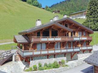 Experience luxury mountain living in this stunning wooden chalet, nestled against a vibrant green hillside.