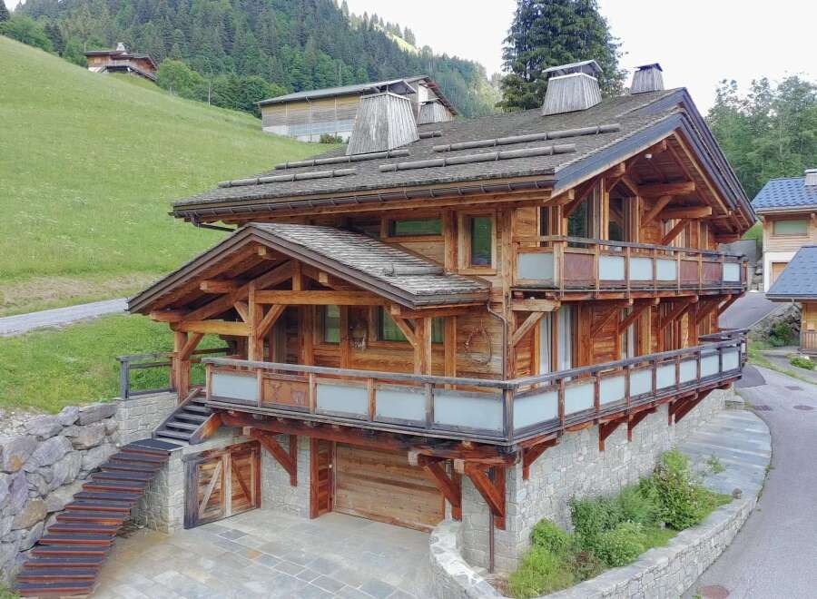 Experience luxury mountain living in this stunning wooden chalet, featuring expansive balconies with frosted glass railings and breathtaking forest views.