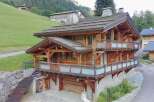 Experience luxury mountain living in this stunning wooden chalet, featuring expansive balconies with frosted glass railings and breathtaking forest views.