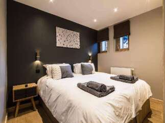 This cozy bedroom features a comfortable bed with soft linens and decorative pillows, perfect for a relaxing stay.
