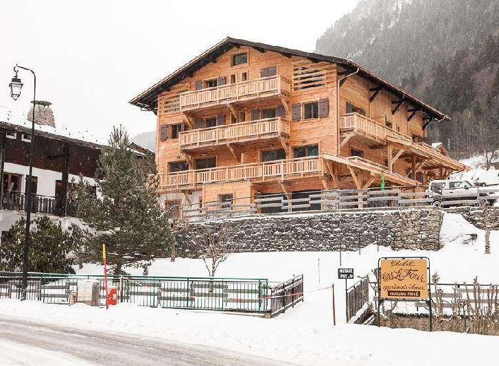 Discover the charm of this stunning wooden chalet nestled in a snowy mountain landscape.