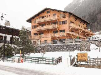 Discover the charm of this stunning wooden chalet nestled in a snowy mountain landscape.