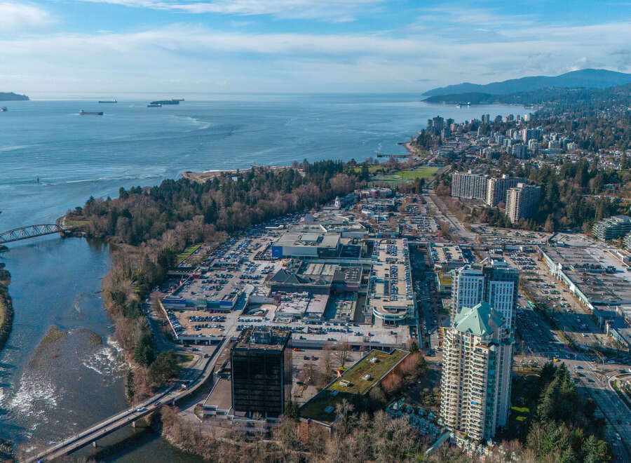 An aerial view showcases a vibrant cityscape nestled along the coast, offering a blend of urban living and natural beauty.