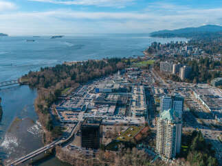 An aerial view showcases a vibrant cityscape nestled along the coast, offering a blend of urban living and natural beauty.