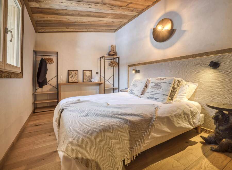 Experience rustic charm in this cozy bedroom, featuring a wooden ceiling and hardwood floors.