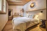Experience rustic charm in this cozy bedroom, featuring a wooden ceiling and hardwood floors.