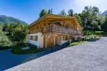 Experience alpine living in this stunning wooden chalet, nestled amidst lush greenery and majestic mountains.
