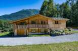 Experience alpine living in this charming wooden chalet, nestled against a backdrop of majestic mountains and lush greenery.